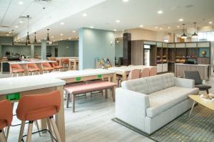 奥兰多Holiday Inn & Suites Orlando - International Dr S, an IHG Hotel的带沙发和桌椅的等候室