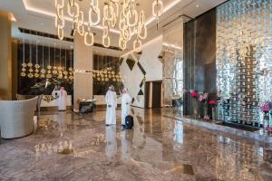 吉达Narcissus Al Hamra Hotel Jeddah的大厅,有两名身着白色长袍的男子站在房间里