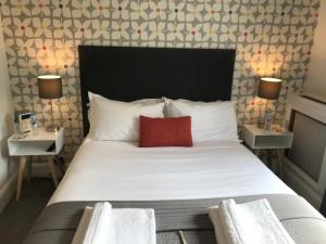 布莱顿霍夫白屋旅馆的一间卧室配有一张带红色枕头的大床