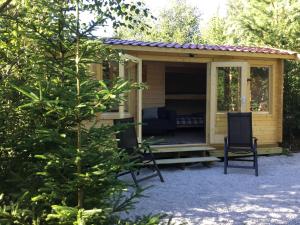 菲利普斯塔德Cozy Lodge near Brattforsheden nature reserve的一个小黄色小屋,设有门廊和椅子