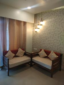 罗纳瓦拉Parishreya Holiday home Lonavala的一间设有两张长椅和枕头的房间