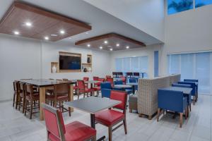 劳德代尔堡Holiday Inn Express Hotel & Suites Fort Lauderdale Airport/Cruise Port, an IHG Hotel的一间带桌椅和电视的用餐室