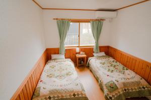轻井泽Guest House Chaconne Karuizawa的带窗户的客房内的两张床