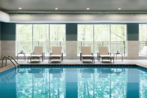 奥本希尔斯Holiday Inn Express - Auburn Hills South, an IHG Hotel的游泳池,带椅子和窗户