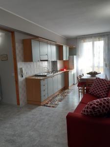 奥特朗托Casa Vacanze Ottantapassi的一间带红色沙发的客厅和一间厨房