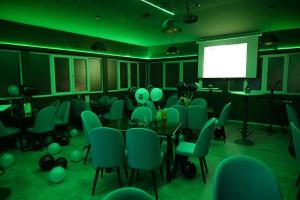 库马诺沃华美伦酒店的一间会议室,配有绿色椅子和屏幕