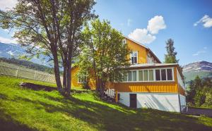Vang I ValdresSommerhotellet的一座种有树木的山丘上的黄色和白色房子