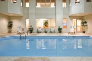 格罗夫城格罗夫城智选假日酒店及套房的酒店的大型游泳池配有桌椅