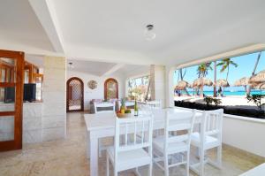 蓬塔卡纳La Flor del Caribe Beach & SPA的一间配备有白色桌椅的用餐室和海滩