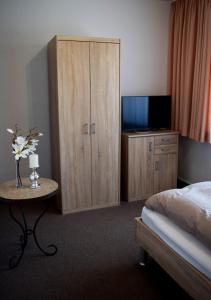 多特蒙德科尔赞的餐厅酒店的一间卧室配有一张床和一个带电视的橱柜