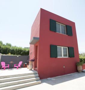 PetrokefaloEntire independent maisonette near Heraklion Pottery Classes的红色的房子,配有粉红色的椅子和桌子
