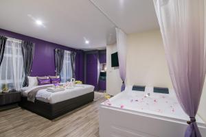 华欣Anchan Hotel & Spa的紫色卧室配有一张床和一个浴缸