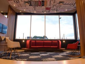 塔图伊Hotel Ibis Tatui的一间位于大窗户前的带红色沙发的等候室