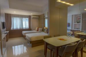 马尼拉Valero Grand Suites by Swiss-Belhotel的酒店客房带一张床、一张桌子和椅子