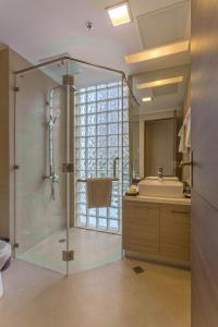 马尼拉Valero Grand Suites by Swiss-Belhotel的一间带玻璃淋浴和水槽的浴室