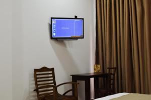 波隆纳鲁沃Monarch Residence的墙上的平面电视,配有桌椅