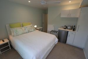 哈海Hahei Pavillion Guest House的一间带白色床的卧室和一间小厨房