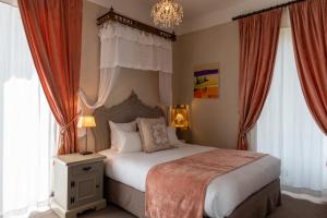盖布维莱尔Domaine de Beaupré - Hotel The Originals Relais的一间卧室配有一张带吊灯和窗户的床。