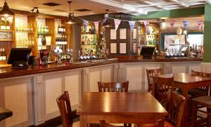 达灵顿Darrington by Greene King Inns的餐厅内带木桌椅的酒吧