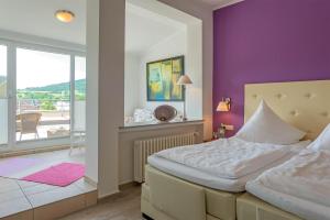 Irrel希尔特主厨酒店的一间卧室配有一张床和紫色的墙壁