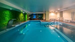圣佩德罗-德尔皮纳塔尔罗多马spa及海水疗养酒店的一座带绿色墙壁的建筑中的游泳池