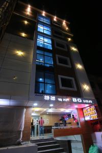 班加罗尔Hotel BG Inn的一座高大的建筑,人们在晚上站在外面