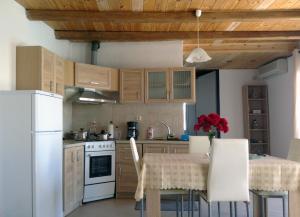 马塔拉Matala Blue的厨房配有木制橱柜和红色鲜花桌