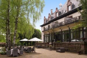 盖布维莱尔Domaine de Beaupré - Hotel The Originals Relais的大楼前带桌子和遮阳伞的天井