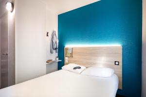 尚尼耶HôtelF1 Angoulême的卧室配有白色的床和蓝色的墙壁