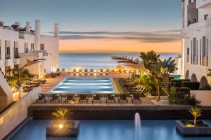 拉戈斯贝勒马Spa及海滩度假酒店的酒店游泳池设有椅子,背景为大海