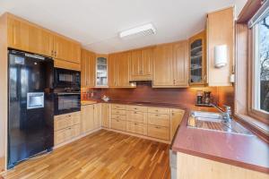 凯于图凯努Goldin的厨房配有木制橱柜和黑色冰箱。