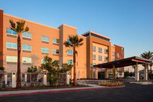 莫雷诺谷Holiday Inn Express & Suites - Moreno Valley - Riverside, an IHG Hotel的一座种植了棕榈树的橙色建筑
