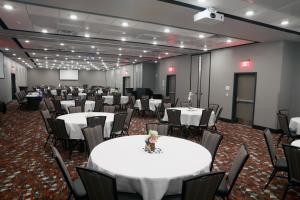 苏福尔斯Holiday Inn & Suites Sioux Falls - Airport, an IHG Hotel的宴会厅配有白色的桌椅