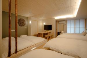 金泽so, KANAZAWA的一间卧室配有两张床和一张桌子及一台电视机