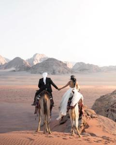 瓦迪拉姆WADI RUM STAR WARS CAMP的骑着骆驼在沙漠中新娘和新郎