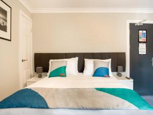 MurtonOYO The Village Inn, Murton Seaham的一间卧室配有一张带蓝色和绿色枕头的大床