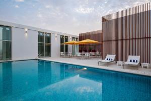 阿可贺巴Staybridge Suites Al Khobar, an IHG Hotel的一个带两把椅子和遮阳伞的游泳池