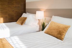 圣毛罗托里内塞格利斯酒店的配有白色床单的酒店客房内的两张床