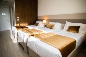 圣毛罗托里内塞格利斯酒店的配有2张位于酒店客房的床铺,配有白色和金色床单