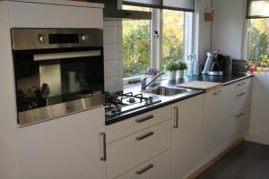SchoorldamRekerlanden 195的厨房配有白色橱柜和炉灶烤箱。