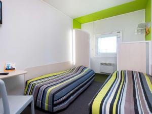 桑斯桑斯诺德一级方程式酒店的两张床位于带绿色和白色墙壁的客房