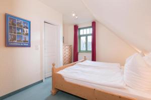 欧巴德伍斯图Ferienhaussiedlung Strandperlen Küstenhof 1d (Typ IV)的一间卧室配有一张带白色床单的床和一扇窗户。