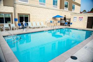 萨凡纳Holiday Inn & Suites - Savannah Airport - Pooler, an IHG Hotel的一个带椅子和桌子的大型游泳池