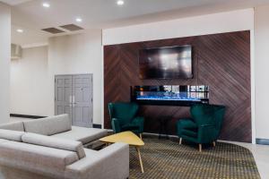 梅萨Holiday Inn & Suites Phoenix-Mesa-Chandler, an IHG Hotel的客厅配有沙发、椅子和电视
