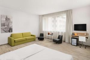 布达佩斯布达佩斯丽笙布鲁酒店的客厅设有黄色沙发和电视