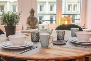 莱比锡Sleepwell Apartment - Klostersuite的木桌,带盘子和杯子,雕像