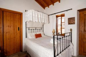 洛弗Constantias stone houses的一间卧室配有一张带白色床单的床和一扇窗户。