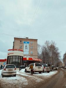 托木斯克ОК! Красноармейская, 101的一条雪覆盖的街道,在建筑物前停放汽车