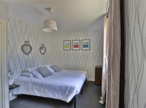 弗勒里Logis Hotel Des Grands Vins的卧室配有白色的床,墙上挂着一些图片