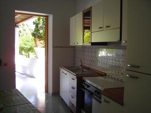 利帕里Villagiuditta Case Vacanze的厨房配有白色橱柜、水槽和门